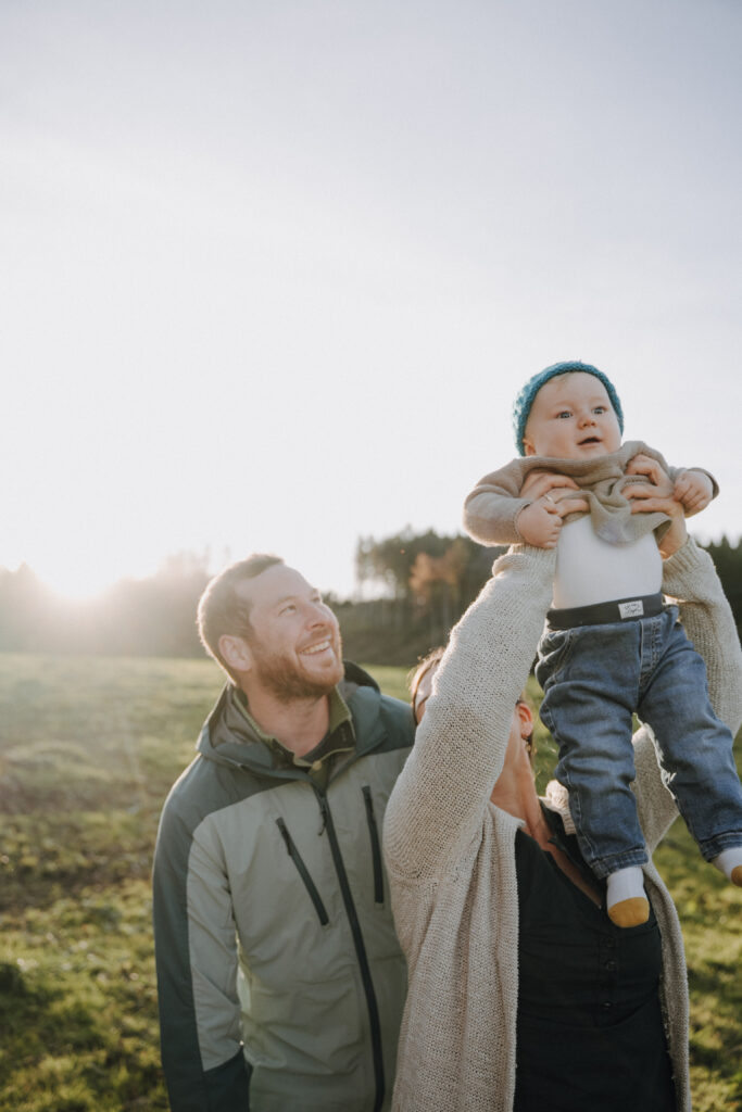 Eltern halten ihr Kind im Arm bei einem Outdoor-Shooting in Wolfegg